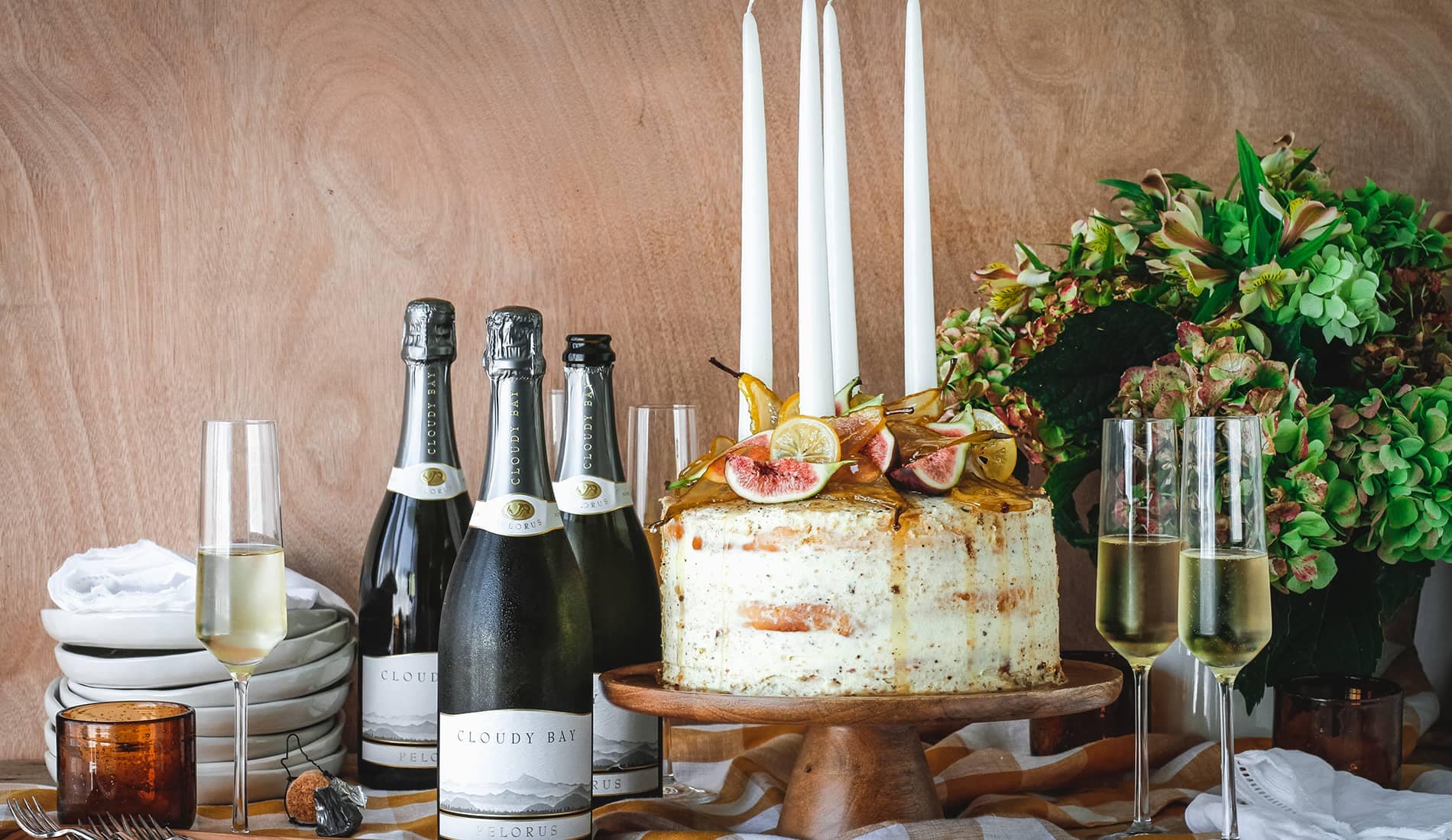Large cake with figs beside 3 bottles and glasses of Cloudy Bay Pelorus 