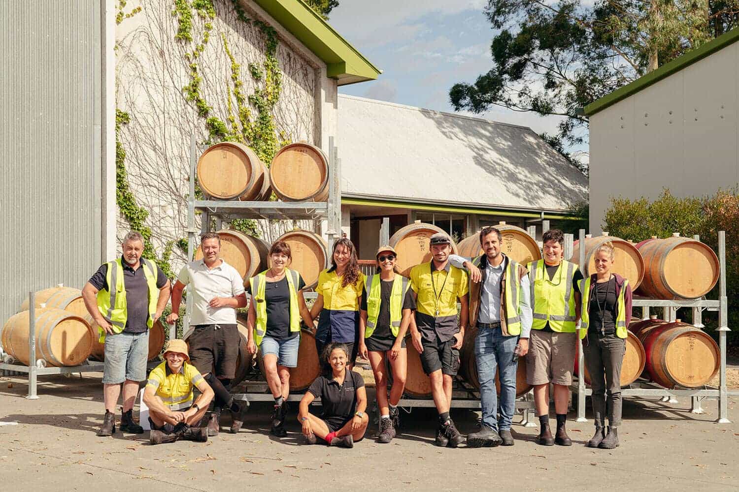 Group photo of Cloudy Bay staff standing in front of wine barrels