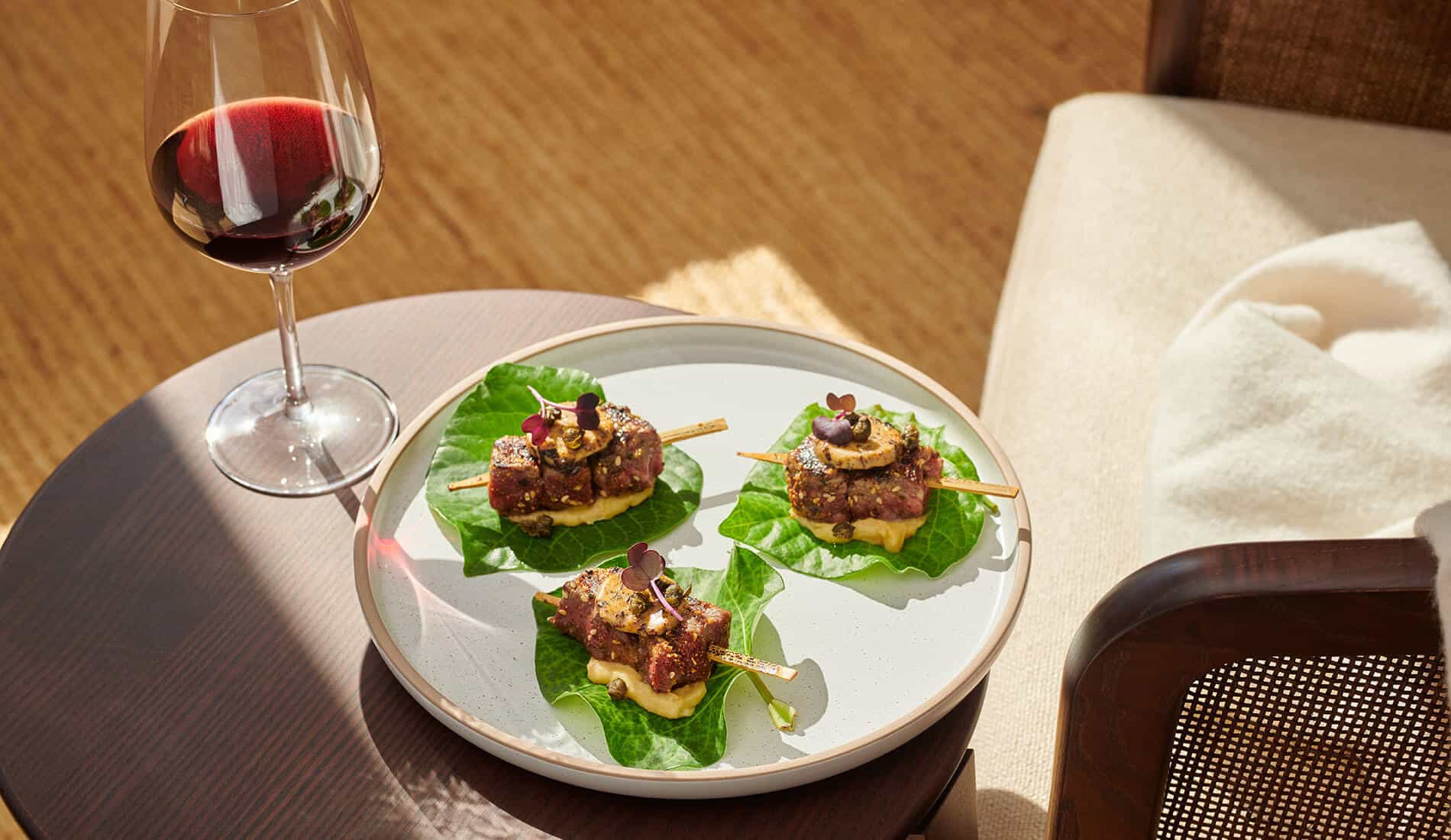 Plate of beef skewers beside glass of red wine