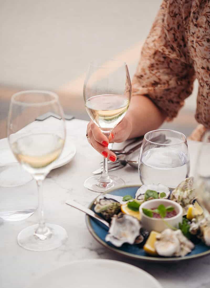 Plate of oysters beside two glasses of white wine