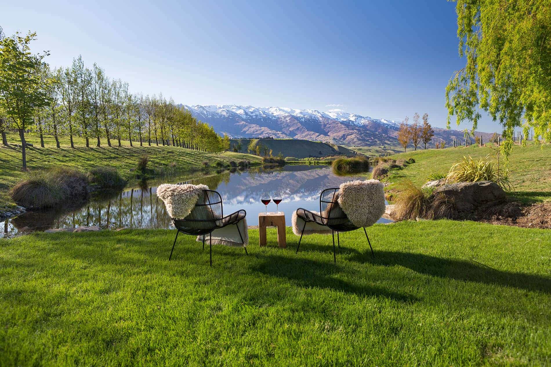 Two chairs on lawn looking over small lake