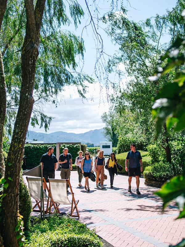 Seven people walking on brick path, flanked by two Cloudy Bay staff