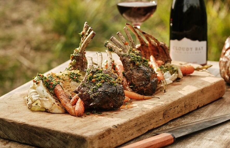 Plate of Lamb Racks with Mint Chimichurri and a bottle of New Zealand Pinot Noir