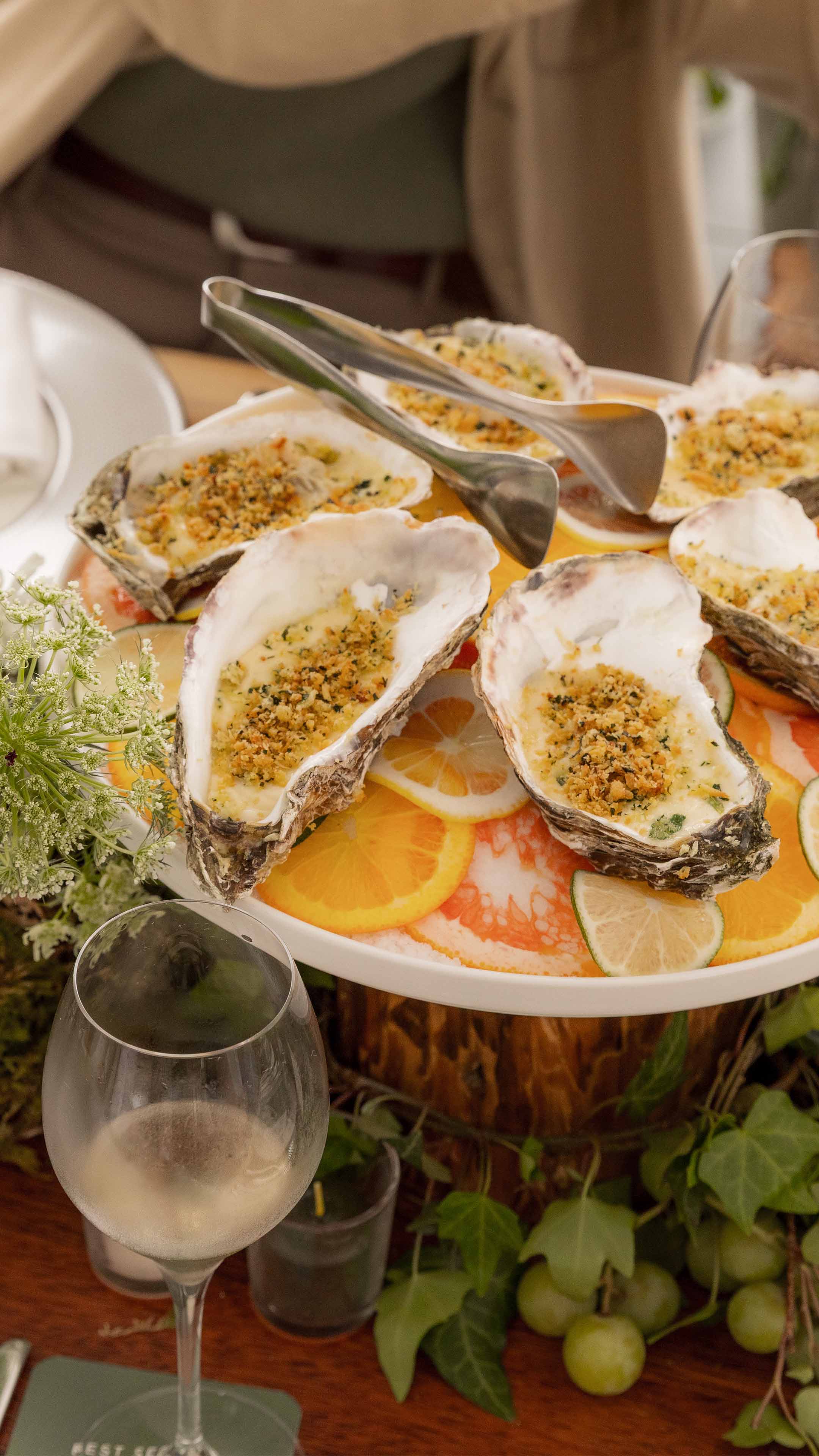 oven-baked oysters on agrum plate with glass of Sauvignon Blanc