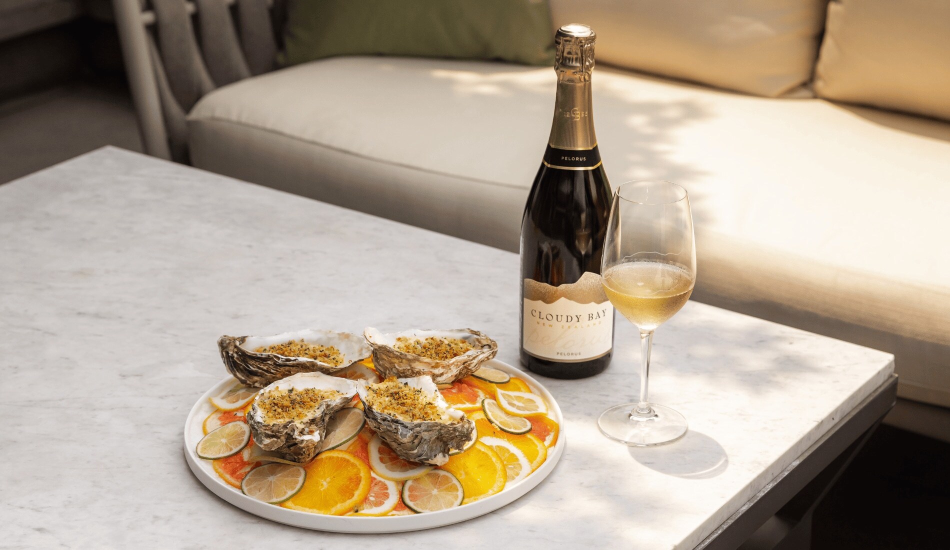 Baked Oysters in a plate with a bottle of Cloudy Bay Pelorus