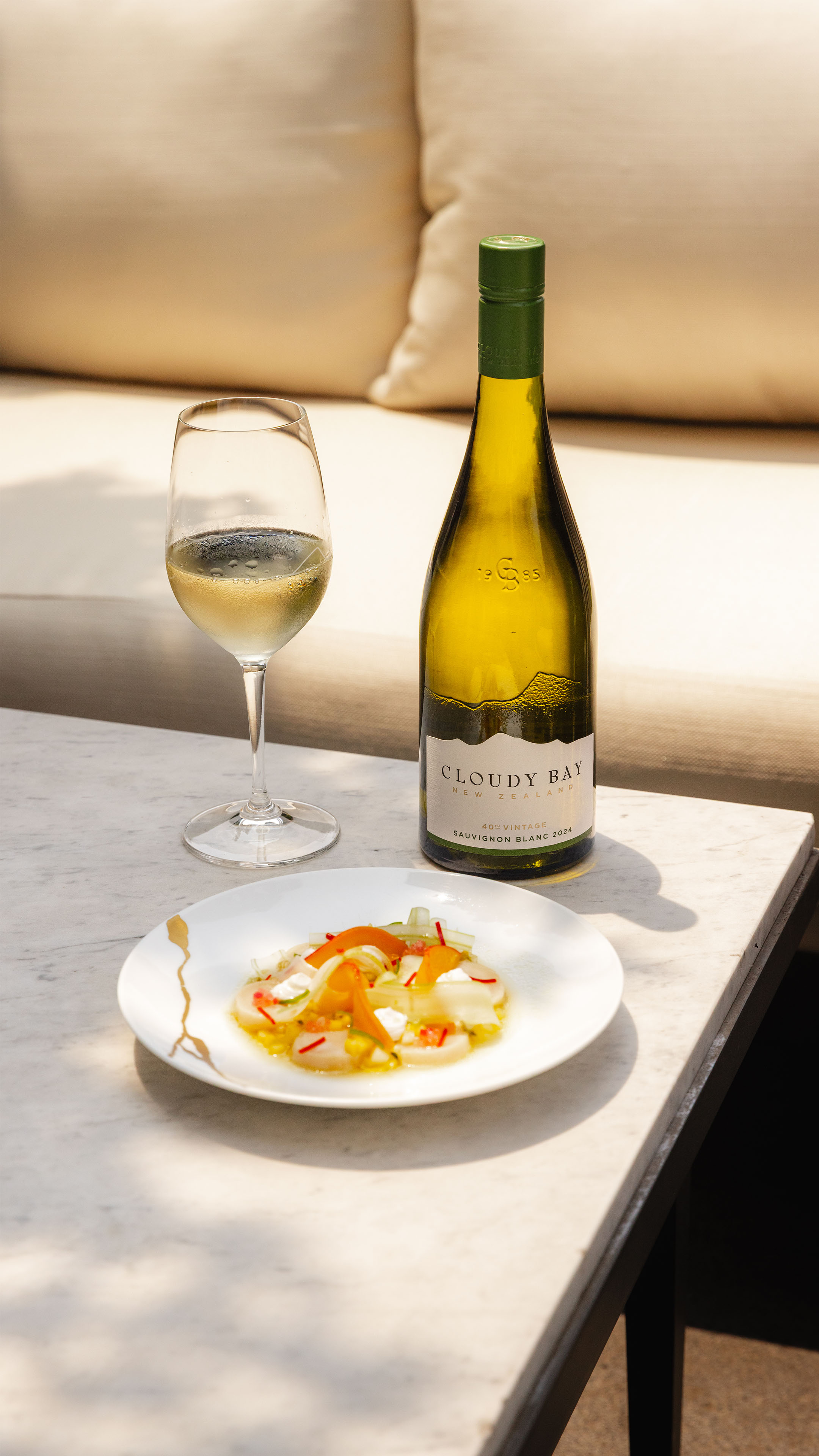 Sunny table with a plate of Scallop ceviche and a bottle of Sauvignon Blanc