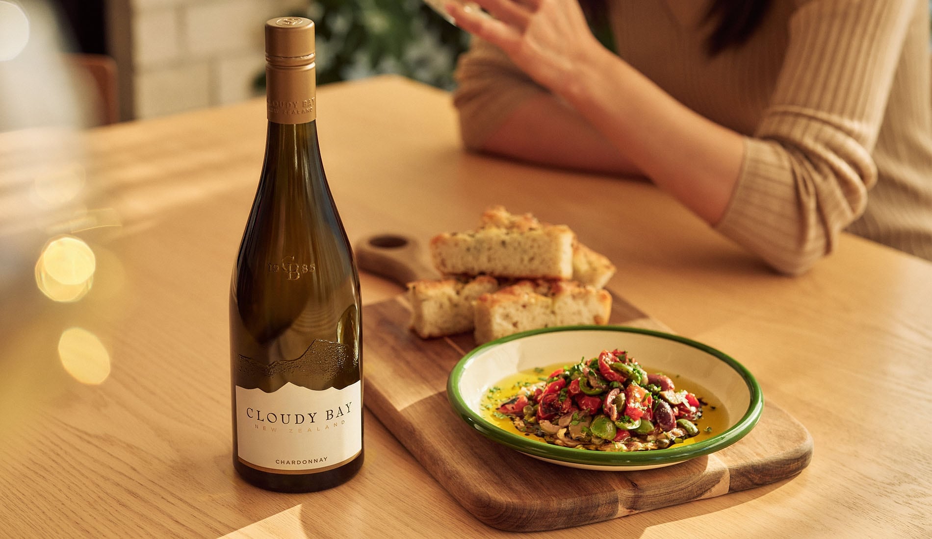 bottle of chardonnay next to foccacia and puttanesca dip