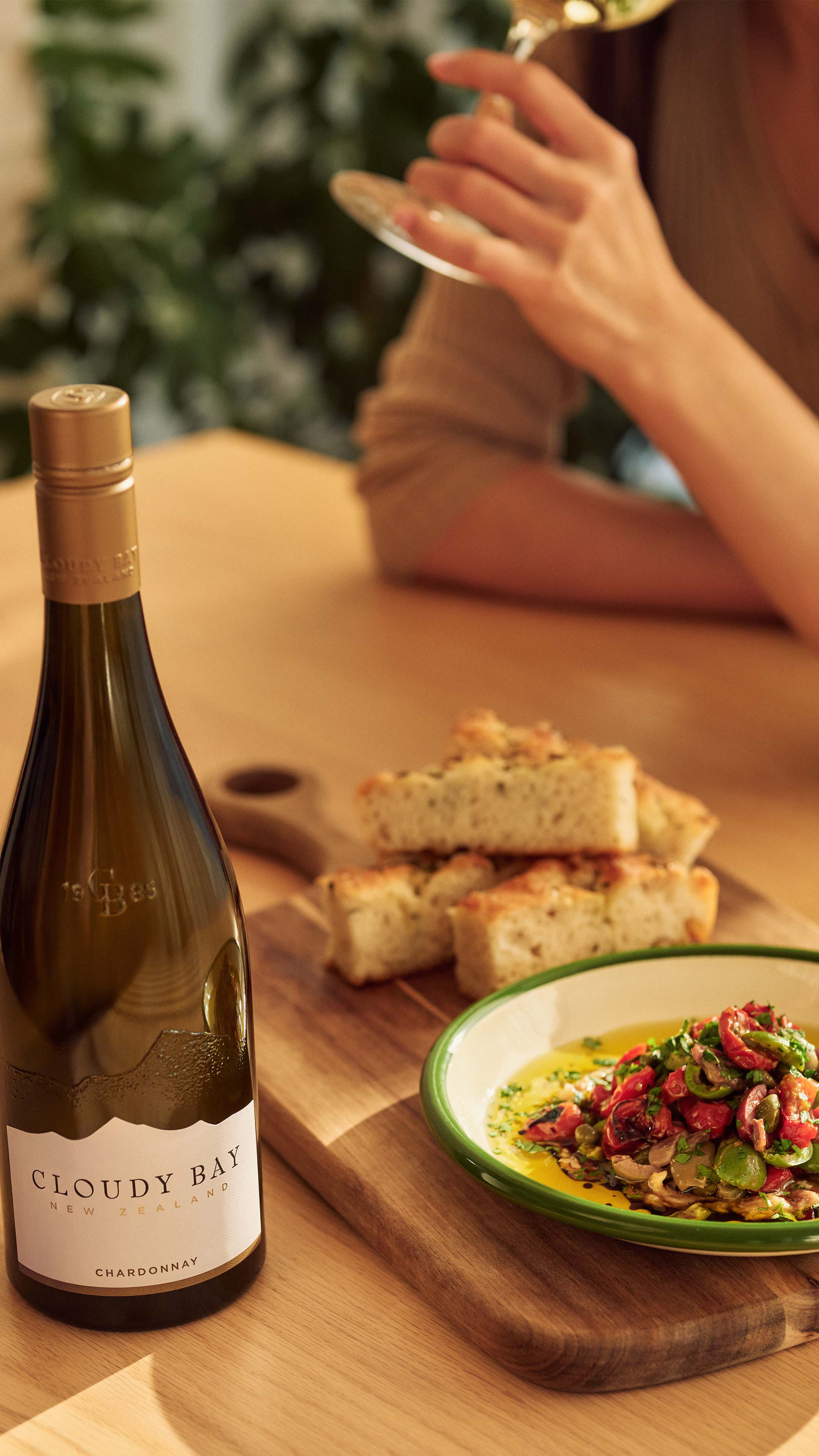 bottle of chardonnay next to foccacia and puttanesca dip
