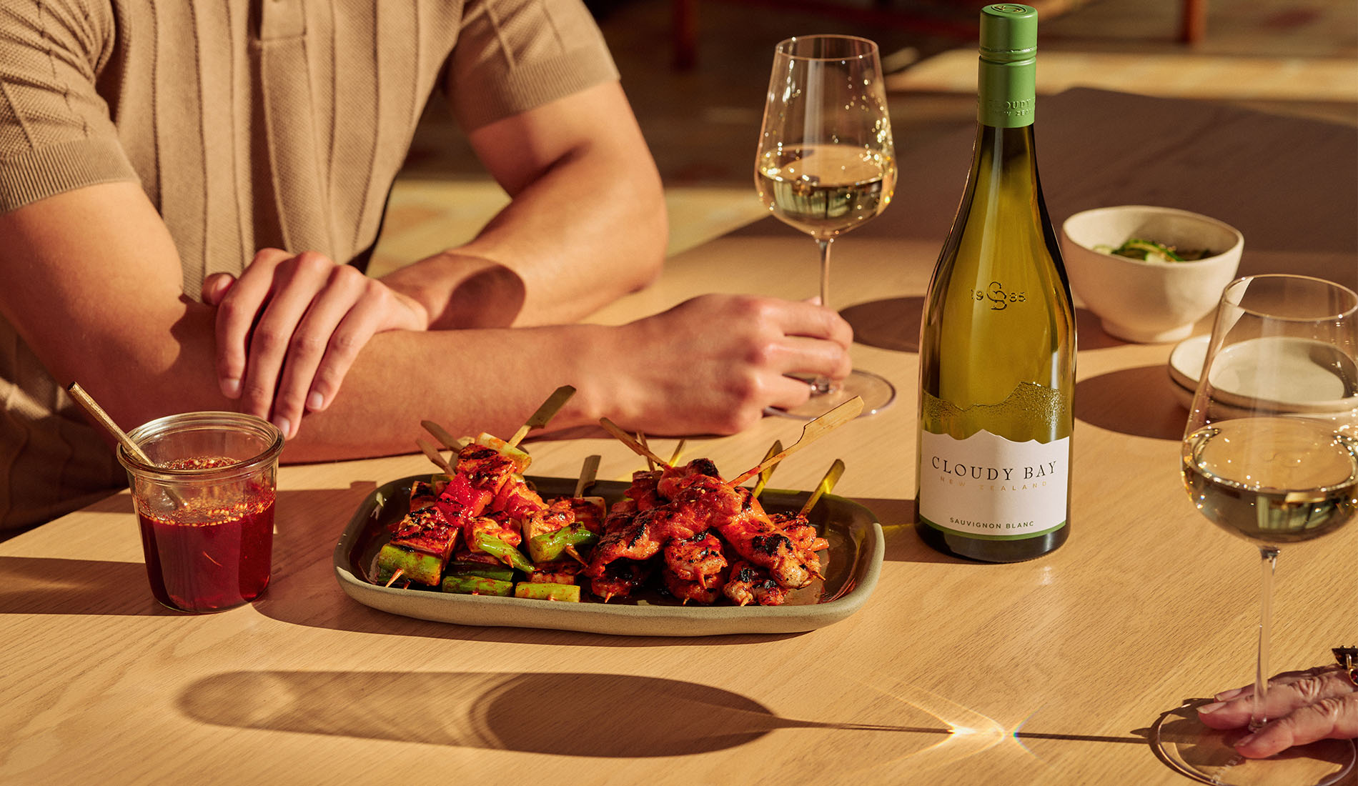 hot honey skewers with glasses and bottle of sauvignon blanc