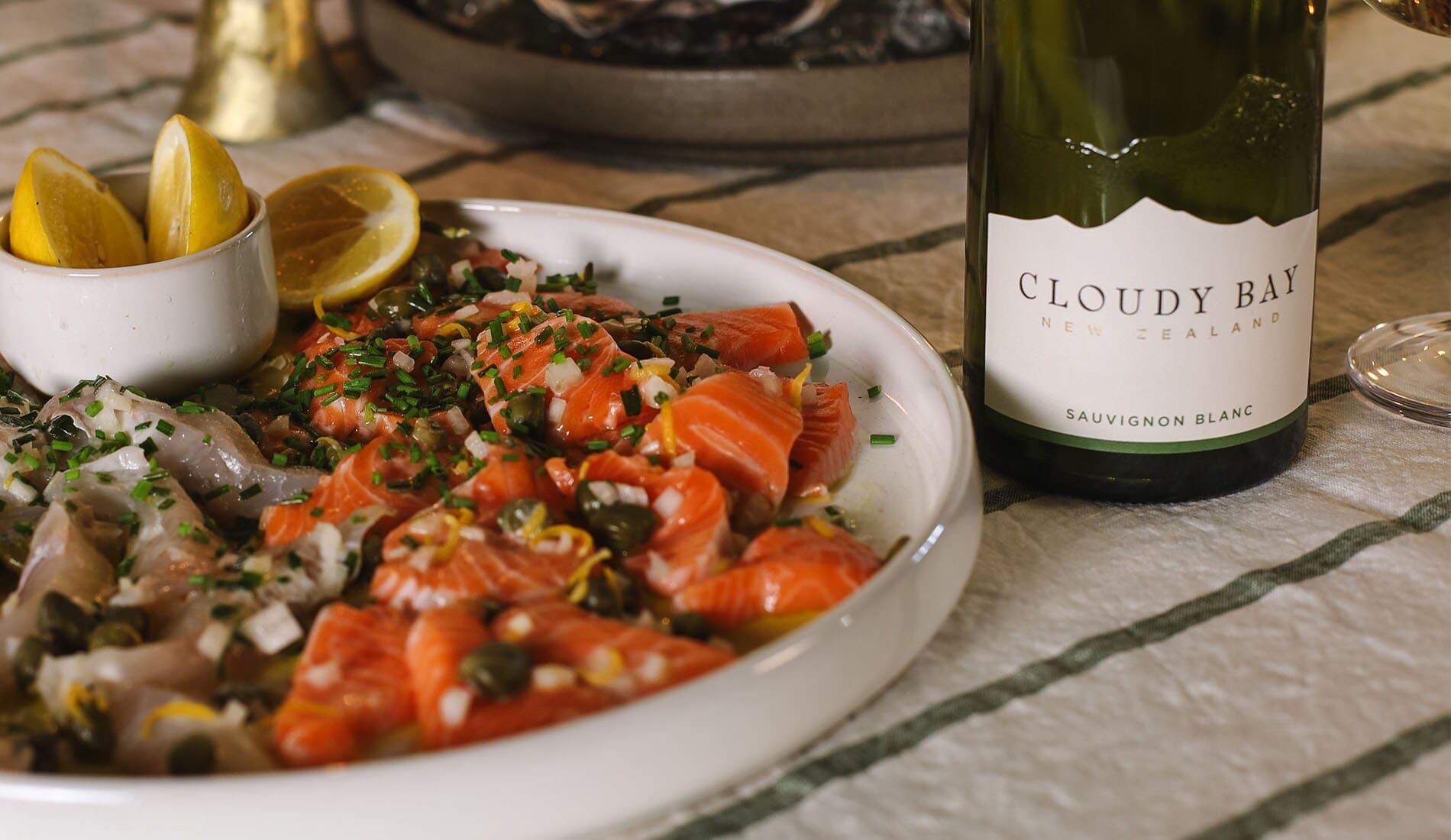 Fish crudo with lemon and a bottle of Cloudy Bay Sauvignon Blanc