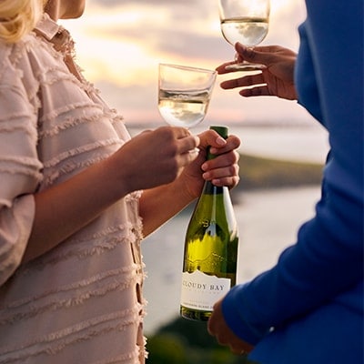 Couple having a drink of Cloudy Bay Sauvignon Blanc in sunset