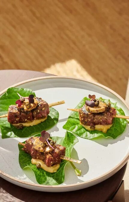 Plate of beef skewers beside glass of red wine