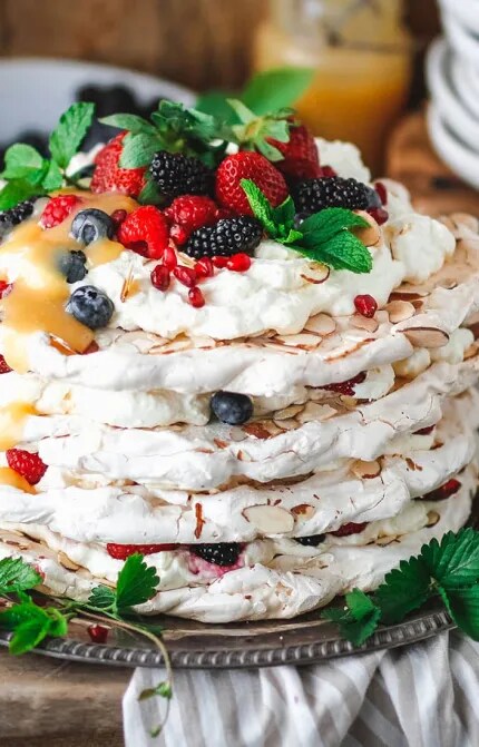 A layered meringue cake with fresh fruit and flaked almonds, and a bottle of Cloudy Bay Pelorus sparkling wine.