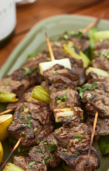 Plate of grilled beef & spring onion skewers with a bottle of Sauvignon Blanc