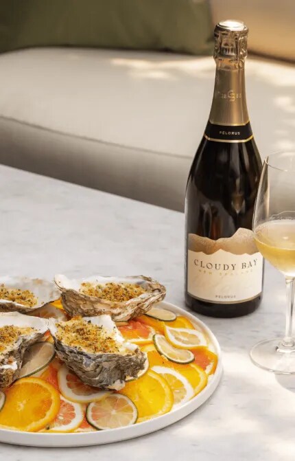 Baked Oysters in a plate with a bottle of Cloudy Bay Pelorus