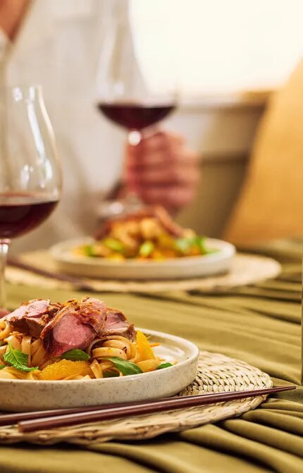 Crispy Duck on noodle salad with glass and bottle of Te Wahi