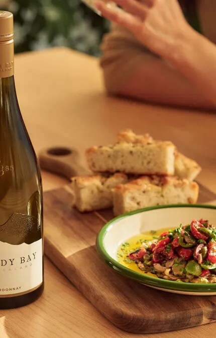 bottle of chardonnay next to foccacia and puttanesca dip