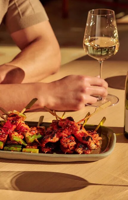 hot honey skewers with glasses and bottle of sauvignon blanc
