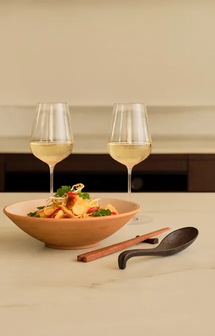 Table with sauvignon blanc glasses and plate of dumplings and noodles